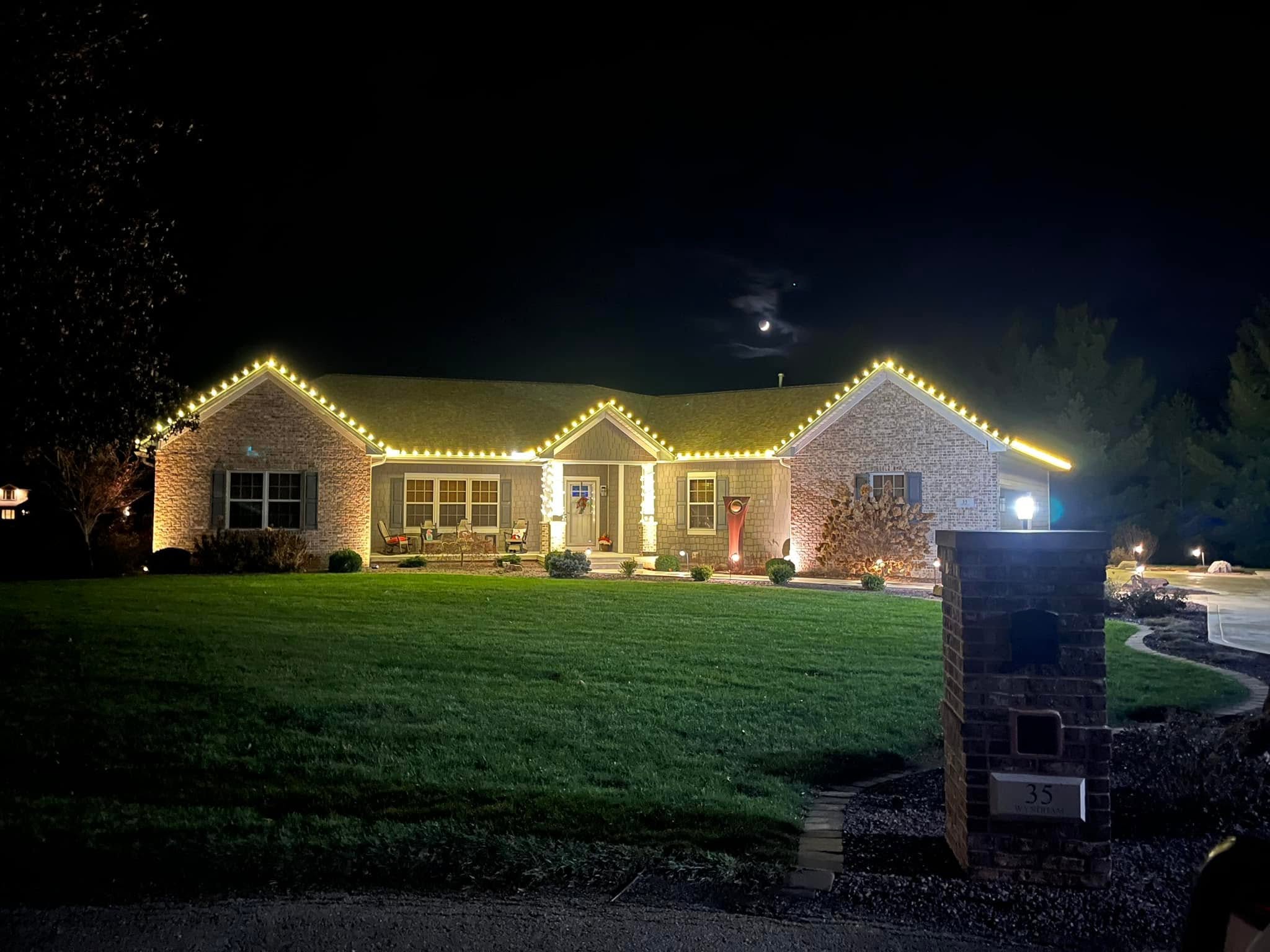 Two-storey home with warm white roofline lighting and lit garage detail
