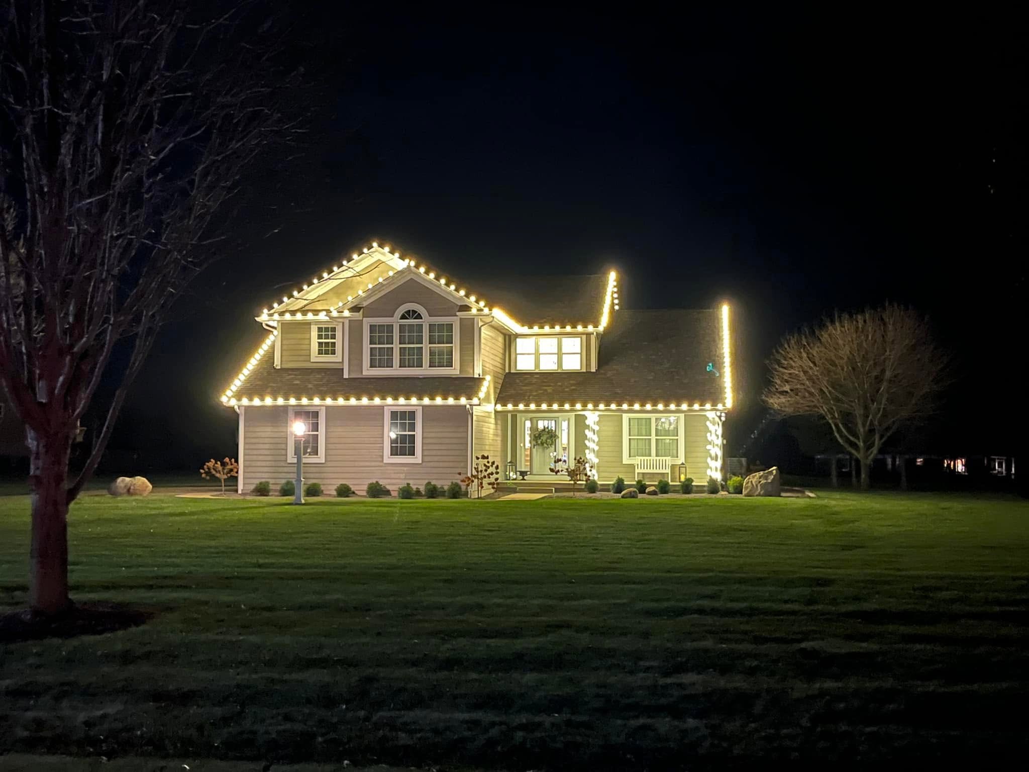 Two-storey home with warm white roofline lighting and wrapped porch columns