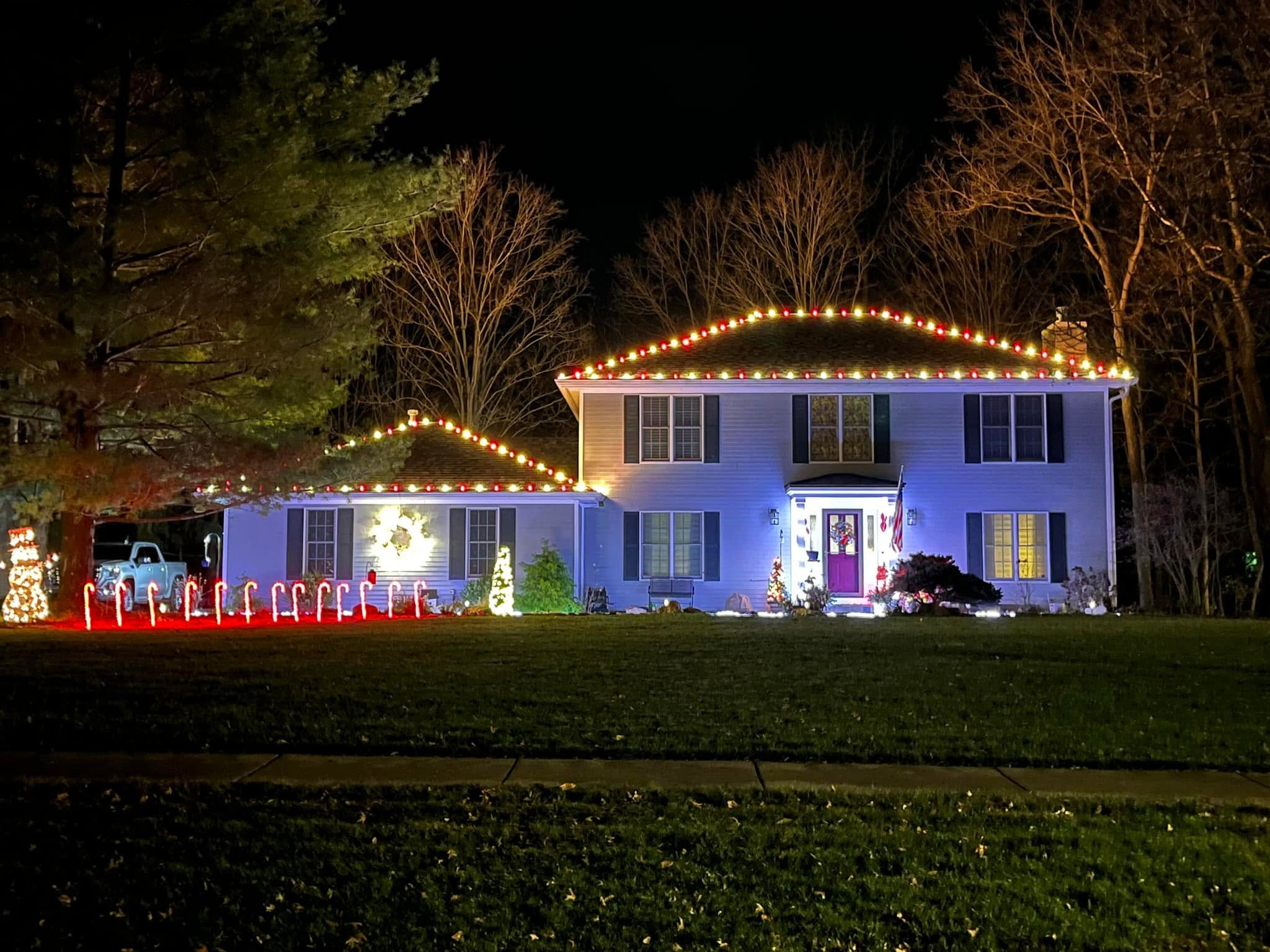 Colonial home outlined in red and warm white C9 bulbs